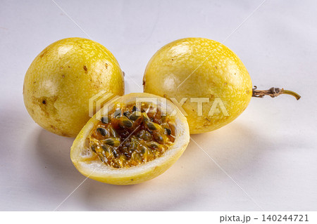 Fresh yellow passion fruit with cut half showing seeds on white background Fresh yellow passion fruit with cut half showing seeds on white background 140244721