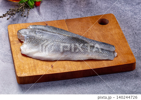 Raw Sea Bass Fillets on Wooden Cutting Board with Herbs Raw Sea Bass Fillets on Wooden Cutting Board with Herbs 140244726