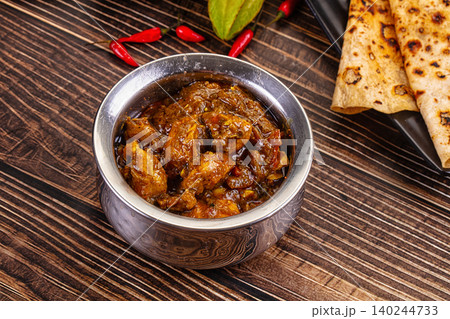 Indian Curry in Metal Bowl with Flatbread and Red Chilies on Wood Indian Curry in Metal Bowl with Flatbread and Red Chilies on Wood 140244733