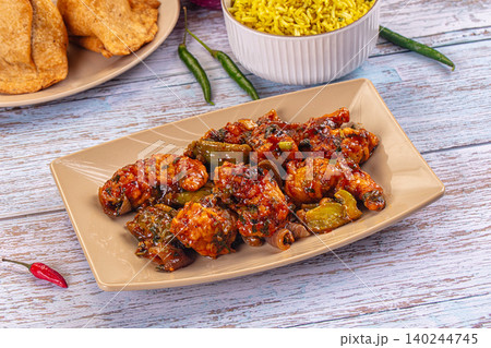 chilli chicken with yellow rice and papadums on wooden table 140244745