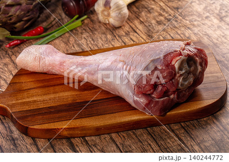Raw turkey leg on wooden cutting board with vegetables Raw turkey leg on wooden cutting board with vegetables 140244772