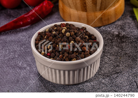 Mixed peppercorns in white bowl with red chili pepper and wooden mortar 140244790