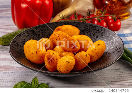 Roasted golden potatoes in black bowl with fresh vegetables Roasted golden potatoes in black bowl with fresh vegetables 140244796