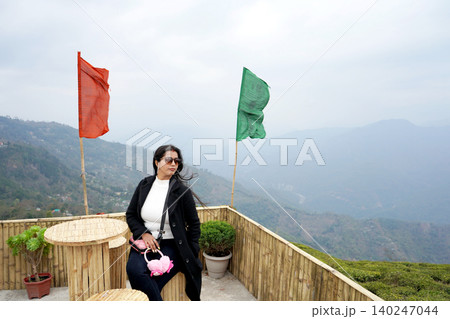 Young woman enjoying a scenic mountain view at a tea garden lookout point at Tinchuley Darjeeling Young woman enjoying a scenic mountain view at a tea garden lookout point at Tinchuley Darjeeling 140247044