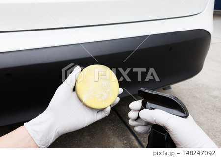 車の樹脂バンパーのお手入れに使うスプレータイプのコーティング剤とスポンジを持つ手元 車の樹脂バンパーのお手入れに使うスプレータイプのコーティング剤とスポンジを持つ手元 140247092