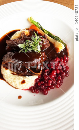 Braised Reindeer Shank with Lingonberries, Root Vegetables and Creamy Mash, Traditional Finnish Cuisine Braised Reindeer Shank with Lingonberries, Root Vegetables and Creamy Mash, Traditional Finnish Cuisine 140248722