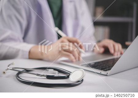 Doctor working on laptop computer with stethoscope on white table. Medical technology, online consultation, and healthcare business concept with copy space for text. Doctor working on laptop computer with stethoscope on white table. Medical technology, online consultation, and healthcare business concept with copy space for text. 140250710