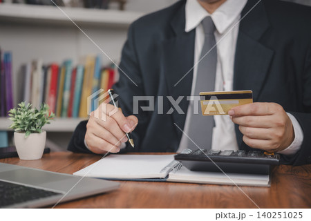 Credit card payment. Businessman holds card using calculator and notebook beside laptop in office, tracking finance, budget, expense, debt, banking, accounting for control. concept personal finance. 140251025