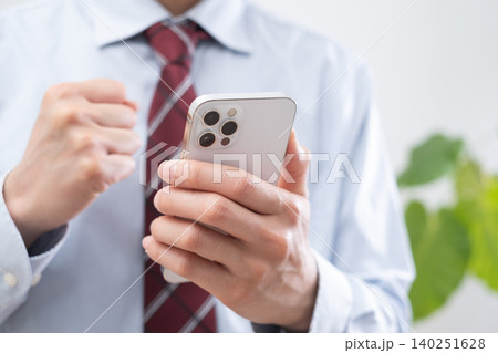 スマホを持ちガッツポーズするビジネスマン 140251628