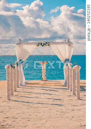 Romantic wedding altar wrapped in soft white drapes facing the open sea. Vertical composition ideal for bridal magazine covers. Intimate beachfront ceremony bathed in tropical sunlight. Picturesque 140252195