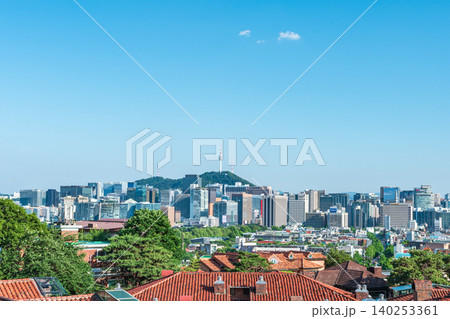 Scenic skyline of downtown Seoul featuring Namsan Seoul Tower and skyscrapers under a clear blue sky with white clouds on a summer day 140253361