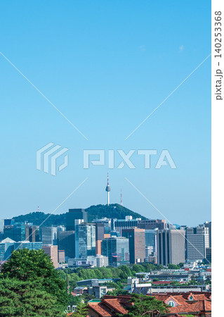 Scenic skyline of downtown Seoul featuring Namsan Seoul Tower and skyscrapers under a clear blue sky with white clouds on a summer day 140253368