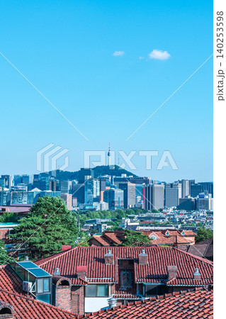 Scenic skyline of downtown Seoul featuring Namsan Seoul Tower and skyscrapers under a clear blue sky with white clouds on a summer day 140253598