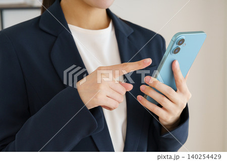スマホを持つ若い日本人女性の手元のアップ スマホを持つ若い日本人女性の手元のアップ 140254429