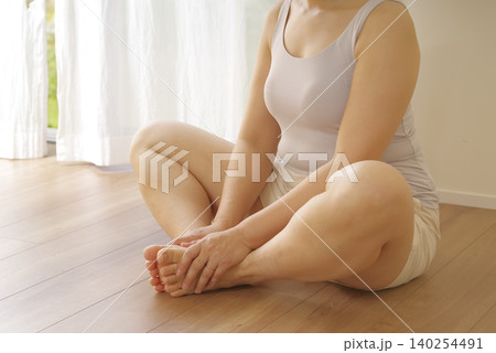 床に座って股関節ストレッチを行う女性 床に座って股関節ストレッチを行う女性 140254491