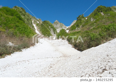 雪渓と青空に浮かぶ新緑と岩峰の山景 雪渓と青空に浮かぶ新緑と岩峰の山景 140255295