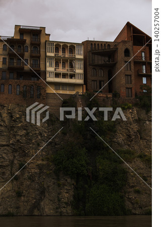 Historic Cliffside Houses Above River Gorge Under Dramatic Storm  140257004