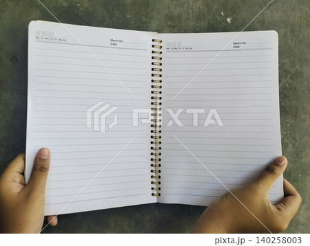 Hand Holding Notebook on Concrete Wall Background Hand Holding Notebook on Concrete Wall Background 140258003