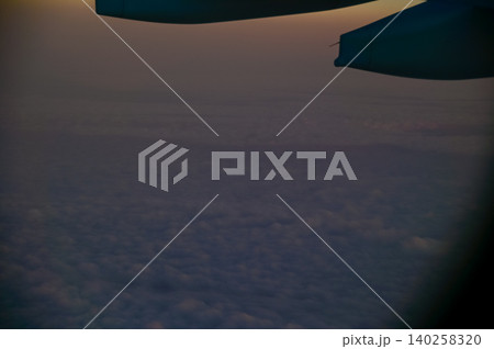 Looking through the airplane window with the sunset sky. Romantic sky, golden hours, colorful sunset sky with clouds. Stunning cloudscape and skyscape. Nature concept. For background use. Looking through the airplane window with the sunset sky. Romantic sky, golden hours, colorful sunset sky with clouds. Stunning cloudscape and skyscape. Nature concept. For background use. 140258320