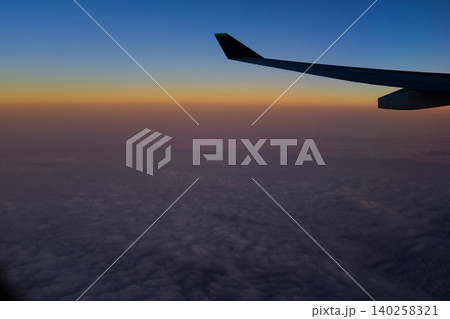Looking through the airplane window with the sunset sky. Romantic sky, golden hours, colorful sunset sky with clouds. Stunning cloudscape and skyscape. Nature concept. For background use. Looking through the airplane window with the sunset sky. Romantic sky, golden hours, colorful sunset sky with clouds. Stunning cloudscape and skyscape. Nature concept. For background use. 140258321