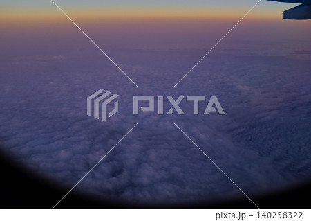Looking through the airplane window with the sunset sky. Romantic sky, golden hours, colorful sunset sky with clouds. Stunning cloudscape and skyscape. Nature concept. For background use. Looking through the airplane window with the sunset sky. Romantic sky, golden hours, colorful sunset sky with clouds. Stunning cloudscape and skyscape. Nature concept. For background use. 140258322