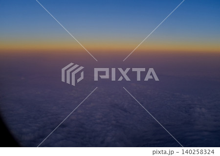 Looking through the airplane window with the sunset sky. Romantic sky, golden hours, colorful sunset sky with clouds. Stunning cloudscape and skyscape. Nature concept. For background use. Looking through the airplane window with the sunset sky. Romantic sky, golden hours, colorful sunset sky with clouds. Stunning cloudscape and skyscape. Nature concept. For background use. 140258324