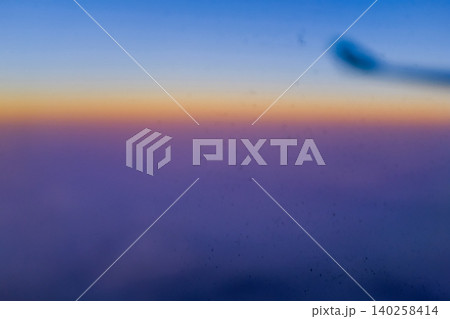 Sunset sky from the airplane window in blur. Romantic sky, golden hours, colorful sunset sky with clouds. Stunning cloudscape and skyscape. Nature and travel concept. For background use. 140258414
