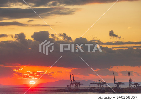 Dramatic sunset over industrial port with cranes and fiery clouds Dramatic sunset over industrial port with cranes and fiery clouds 140258867
