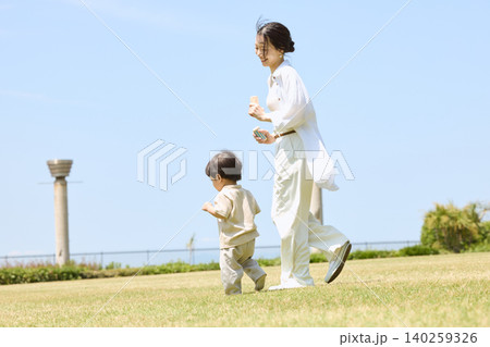 晴れた日の芝生の公園で歩く母親と幼い息子 晴れた日の芝生の公園で歩く母親と幼い息子 140259326