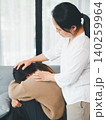 Asian caregiver comforting an upset young woman resting on a sofa at home, showing emotional care, family support, stress relief, empathy, mental wellness, and safe comforting touch. 140259964