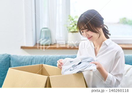 段ボールを開けて届いた商品を確認する女性 140260118
