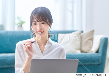 リビングでパソコンを見て笑顔になる若い女性 リビングでパソコンを見て笑顔になる若い女性 140260181