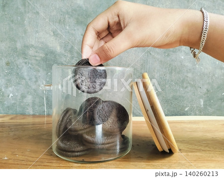 Hands Holding a Glass Jar Filled with Chocolate Sandwich Cookies Hands Holding a Glass Jar Filled with Chocolate Sandwich Cookies 140260213