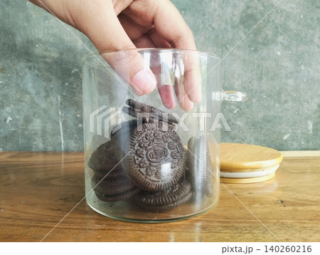 Hands Holding a Glass Jar Filled with Chocolate Sandwich Cookies Hands Holding a Glass Jar Filled with Chocolate Sandwich Cookies 140260216