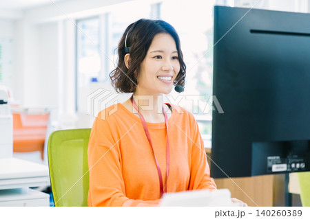オフィスでヘッドセットをつけて応対する女性オペレーター オフィスでヘッドセットをつけて応対する女性オペレーター 140260389