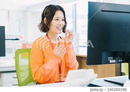 オフィスでヘッドセットをつけて応対する女性オペレーター オフィスでヘッドセットをつけて応対する女性オペレーター 140260396
