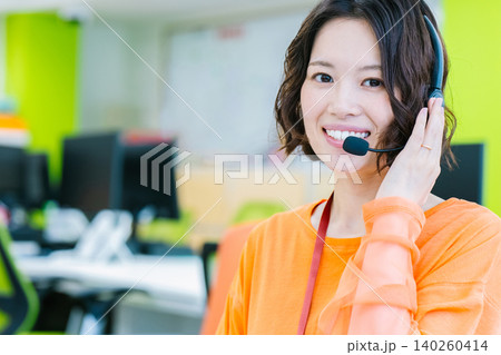 オフィスでヘッドセットをつけて応対する女性オペレーター オフィスでヘッドセットをつけて応対する女性オペレーター 140260414