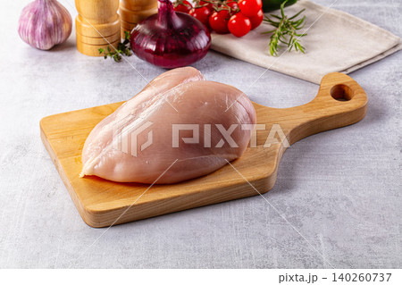 Raw chicken breast on wooden cutting board with fresh vegetables Raw chicken breast on wooden cutting board with fresh vegetables 140260737