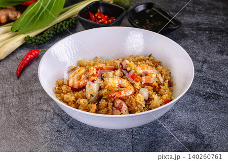 Thai fried rice with shrimp and squid in white bowl on dark stone background with fresh ingredients Thai fried rice with shrimp and squid in white bowl on dark stone background with fresh ingredients 140260761