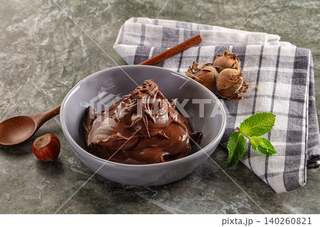 Chocolate hazelnut spread in gray bowl with fresh mint leaf and cinnamon stick on checkered napkin Chocolate hazelnut spread in gray bowl with fresh mint leaf and cinnamon stick on checkered napkin 140260821