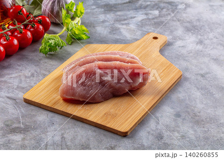 Raw chicken breast fillets on wooden cutting board with vegetables Raw chicken breast fillets on wooden cutting board with vegetables 140260855