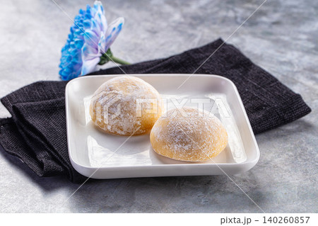 Two powdered sugar donuts on white plate with blue flower 140260857