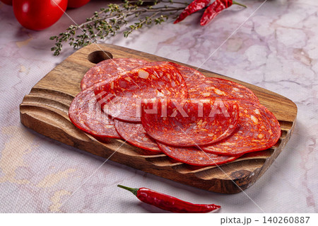 Sliced pepperoni salami on wooden board with chili peppers and tomatoes Sliced pepperoni salami on wooden board with chili peppers and tomatoes 140260887