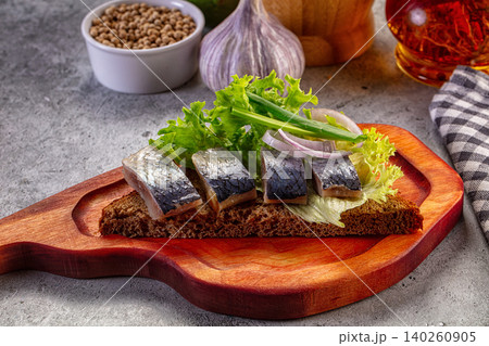 Herring fillets on dark bread with lettuce and onion on wooden board Herring fillets on dark bread with lettuce and onion on wooden board 140260905