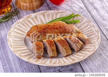 Roasted duck breast sliced on plate with green onions and rosemary 140260936