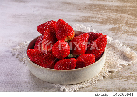Fresh ripe strawberries in a rustic ceramic bowl on a light table Fresh ripe strawberries in a rustic ceramic bowl on a light table 140260941
