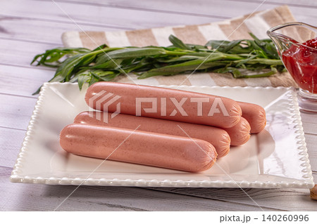 Raw sausages on white plate with fresh herbs and ketchup Raw sausages on white plate with fresh herbs and ketchup 140260996