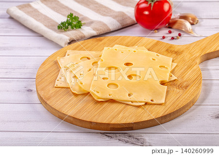 Slices of Swiss Cheese on Wooden Board with Fresh Ingredients 140260999