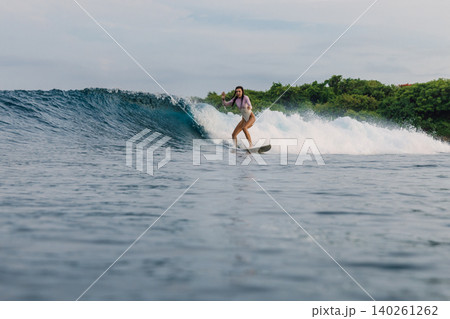 Surfer woman rides on wave on surfboard in ocean, aquatic sport Surfer woman rides on wave on surfboard in ocean, aquatic sport 140261262