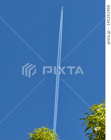 Airplane leaving twin contrails in a clear blue sky 140261466